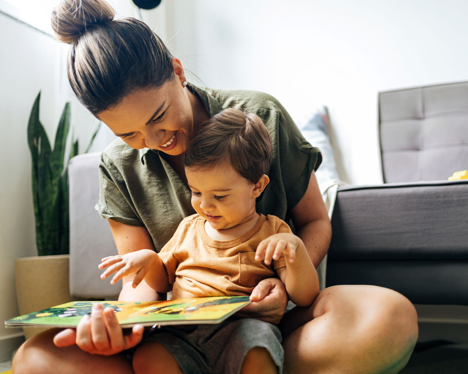A mom reading a picture book with her toddler on the living room floor