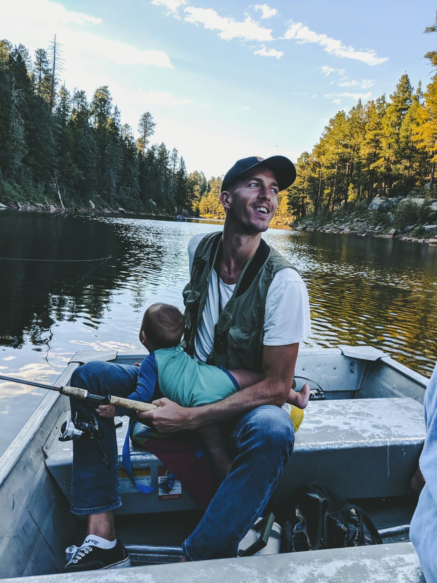 A dad and his son fishing from a small boat on a lake