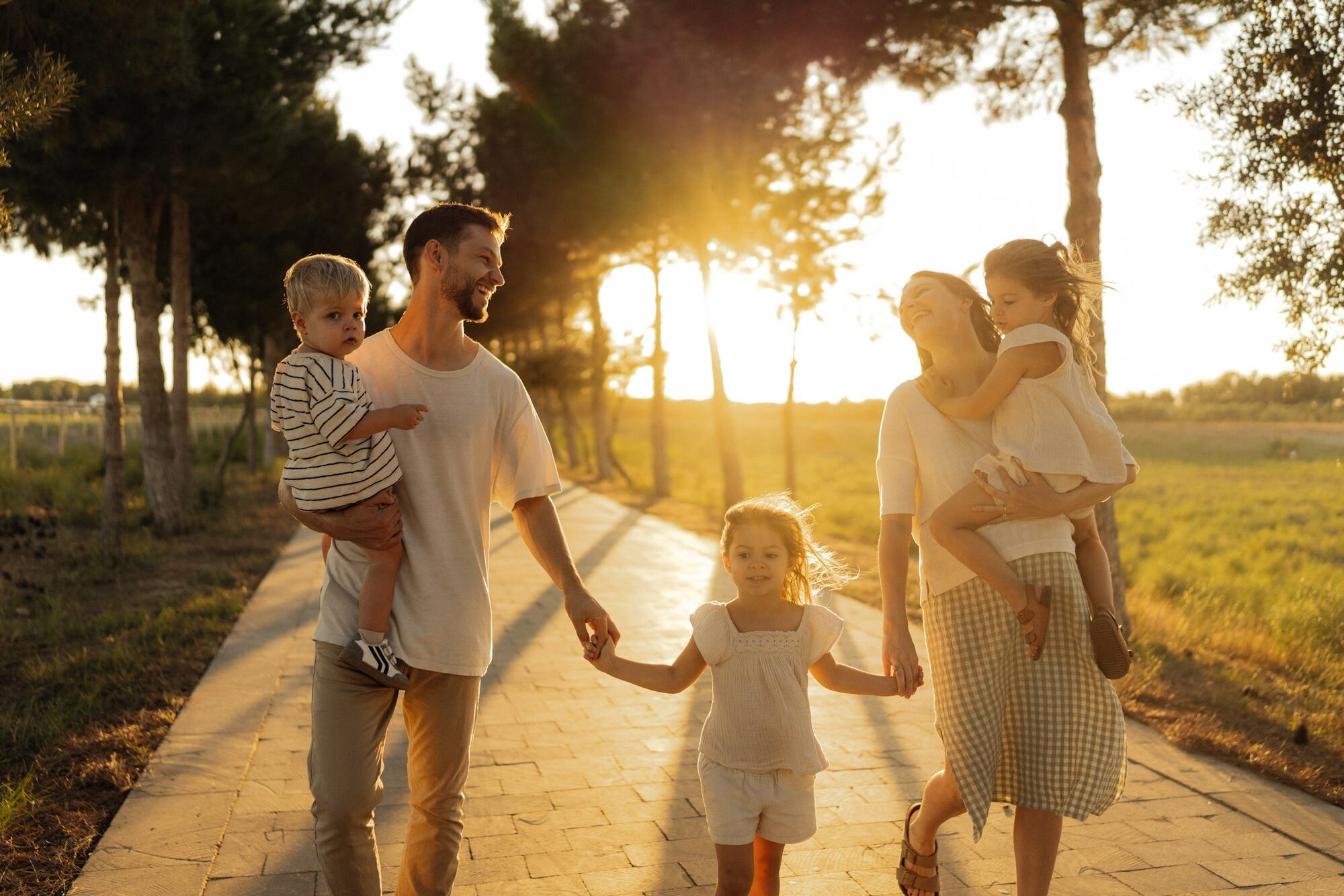 A family walking down a country road at sunset, holding hands