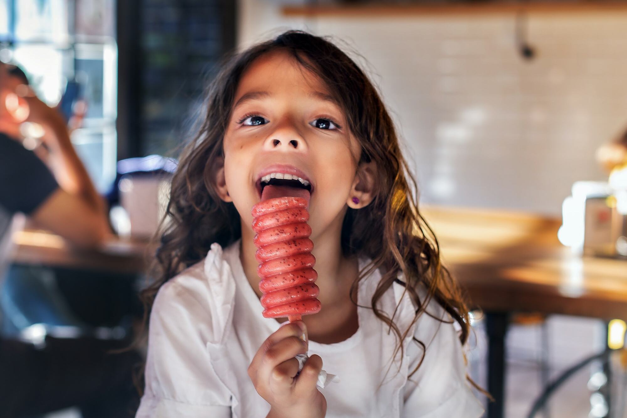 A girl laughing with a red popsicle