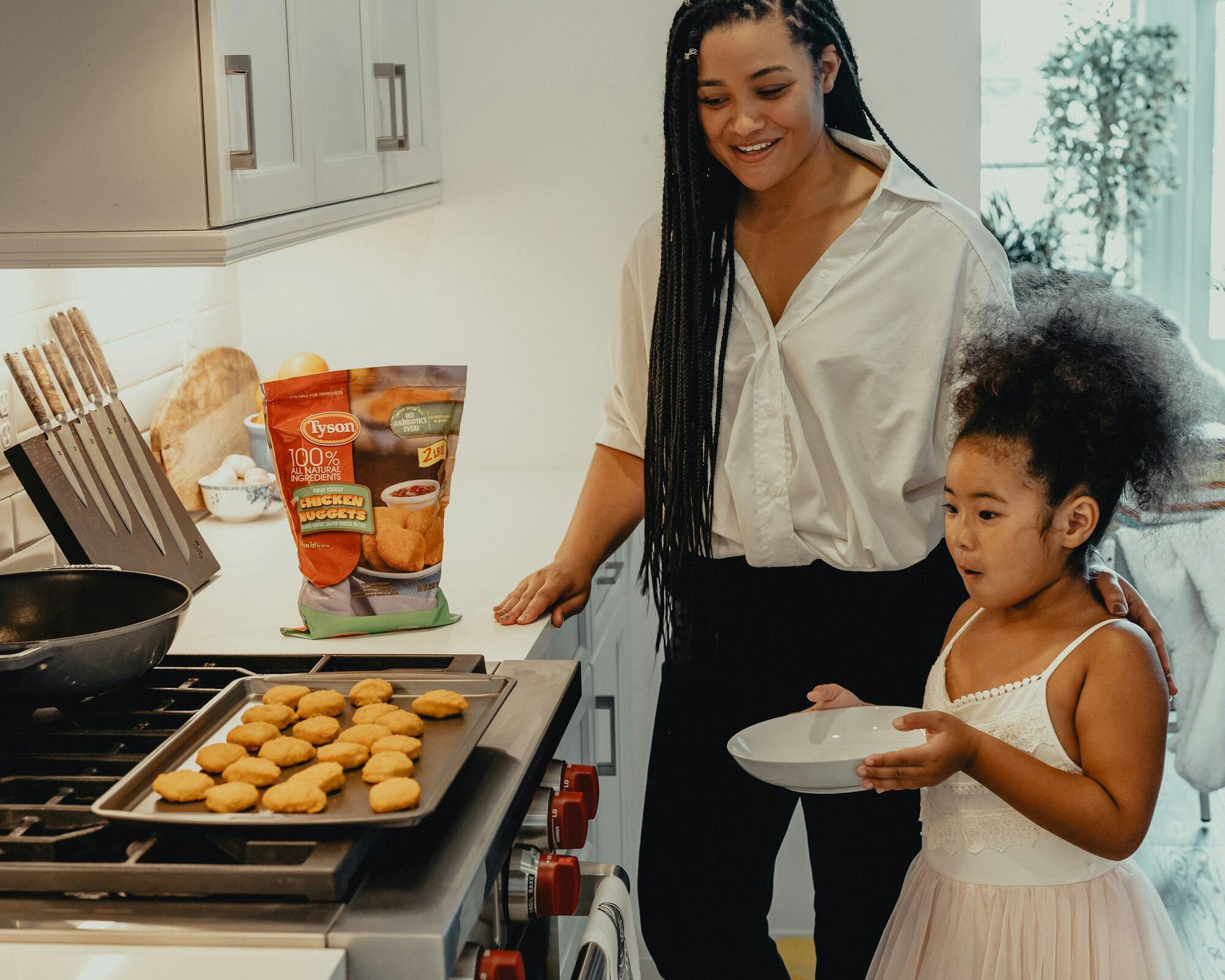 A mom and her daughter baking cookies in the kitchen
