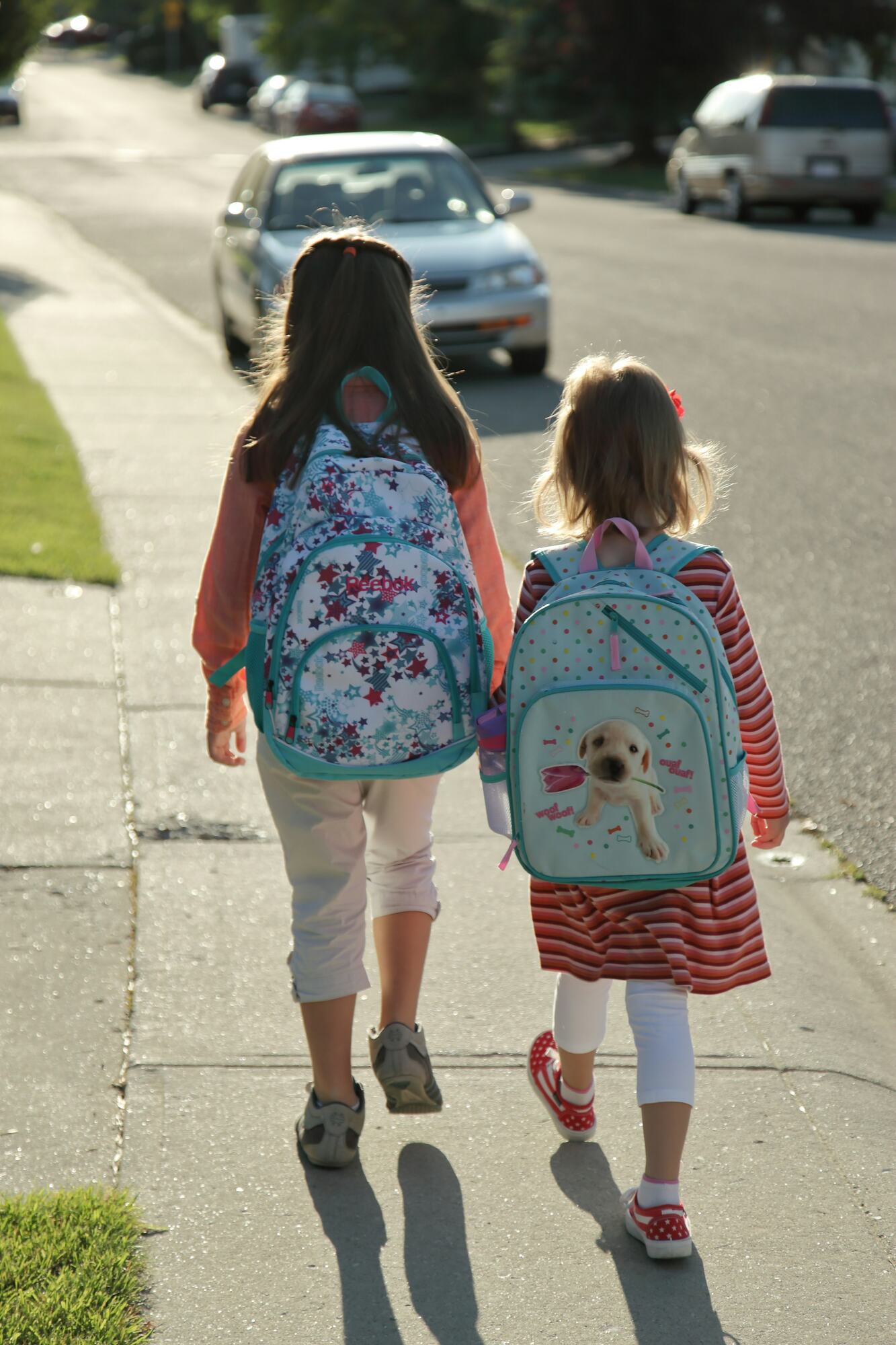 Two sisters with backpacks walking to school
