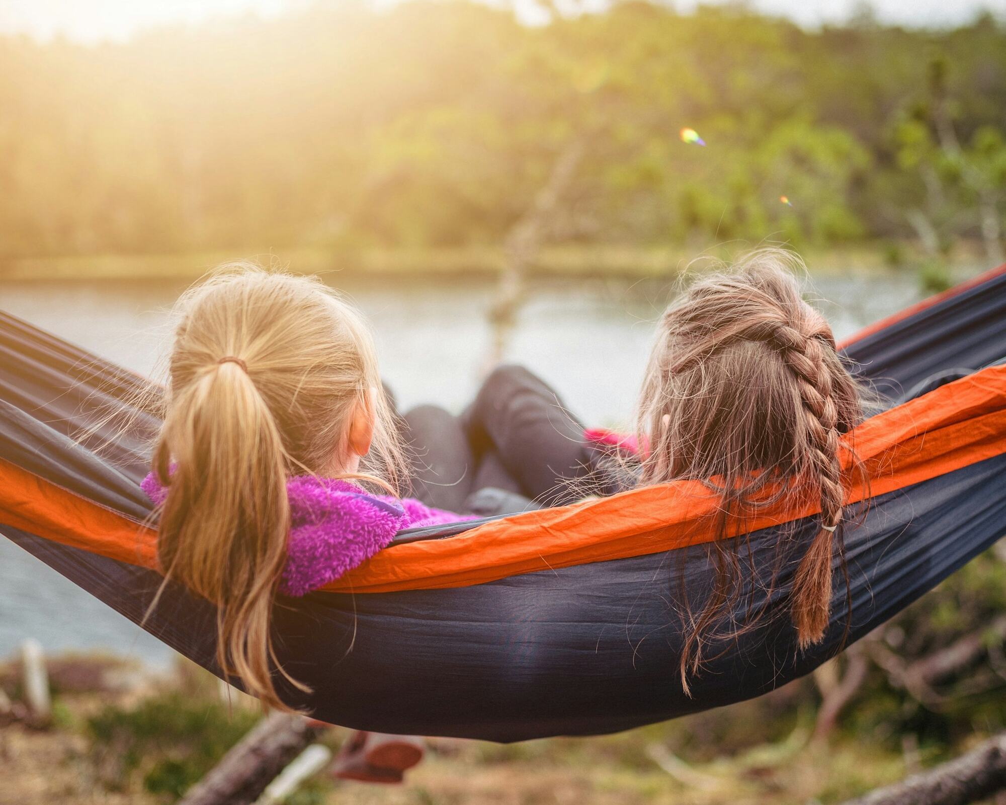Two sisters relaxing in a hammock by a lake