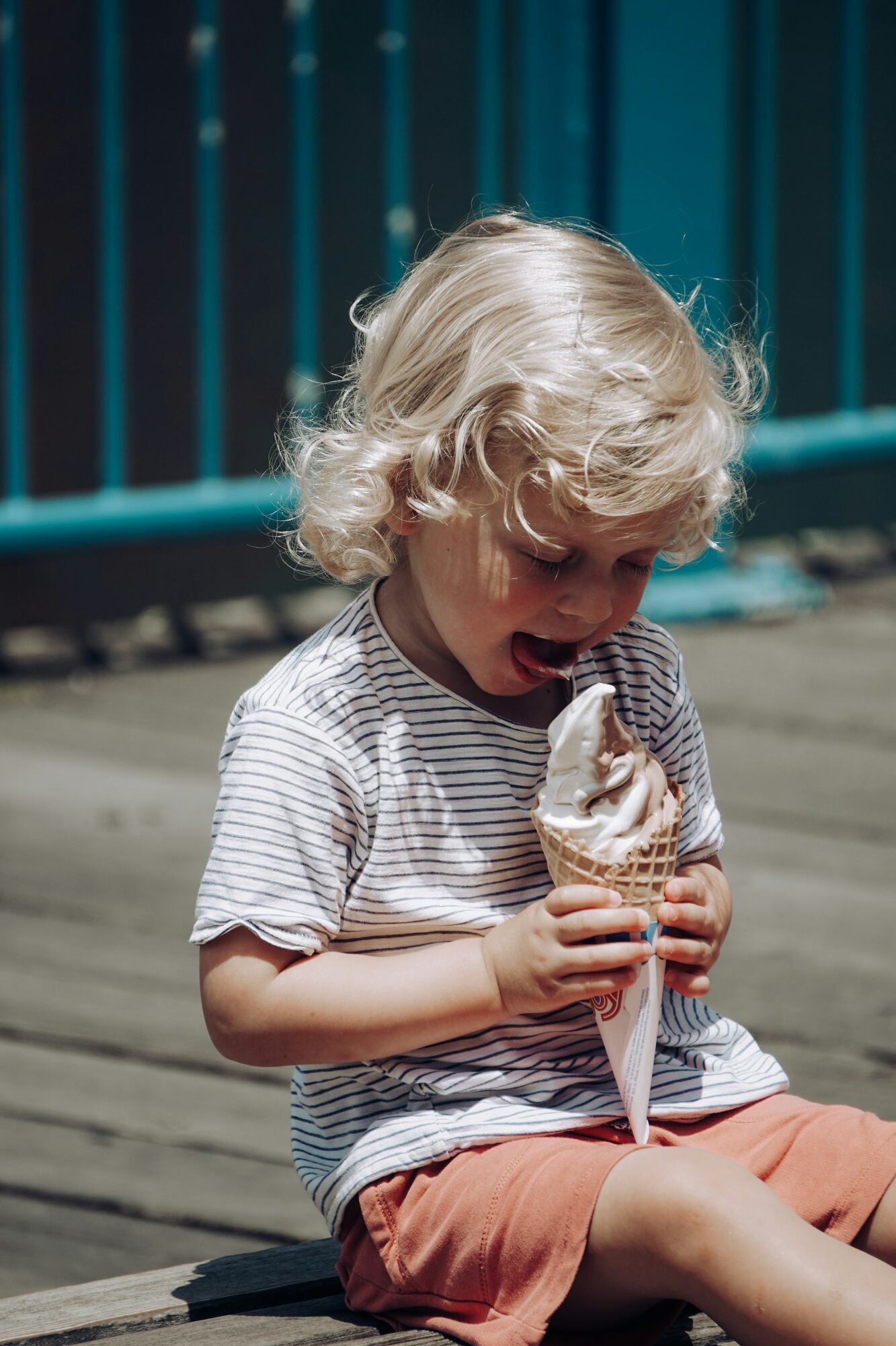A curly haired toddler eating an ice cream cone